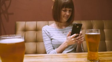 Hareket eden telefon. Bir kız bir barda bir cep telefonunun ekranında görünüyor