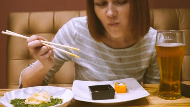 一个寿司店的女孩吃寿司喝啤酒 — 图库视频影像