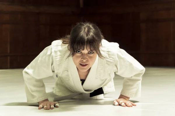 En flicka i en kimono knådar innan träningen i judo och jujutsu — Stockfoto