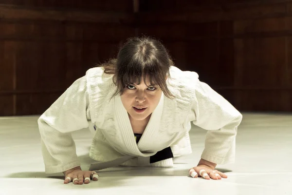 En flicka i en kimono knådar innan träningen i judo och jujutsu Stockbild
