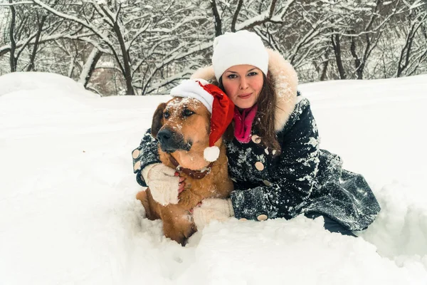 Zima. Dívka se psem v hat Santa Claus — Stock fotografie