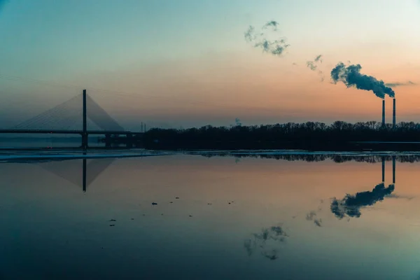 The smoky plant on the background of the river and the setting s — Stock Photo, Image