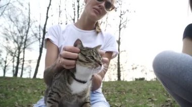 Kedi bir leash üzerinde. Bir kız omuzunda oturur bir kedi ile yürüyor