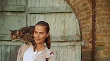Kedi bir leash üzerinde. Bir kız omuzunda oturur bir kedi ile yürüyor