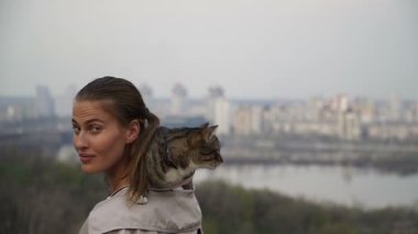 Kedi bir leash üzerinde. Bir kız omuzunda oturur bir kedi ile yürüyor