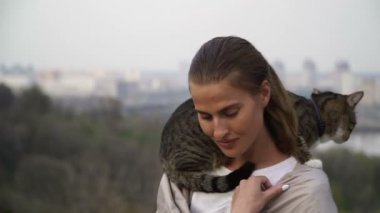 Kedi bir leash üzerinde. Bir kız omuzunda oturur bir kedi ile yürüyor