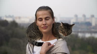Kedi bir leash üzerinde. Bir kız omuzunda oturur bir kedi ile yürüyor