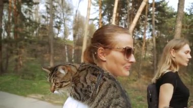 Kedi bir leash üzerinde. Bir kız omuzunda oturur bir kedi ile yürüyor