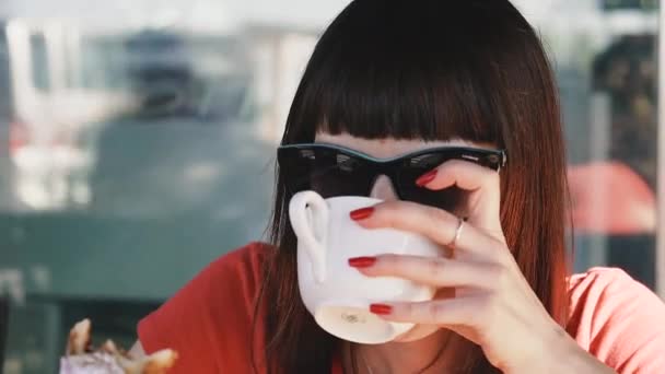 咖啡和糖果 一个女孩坐在海边的咖啡店里 喝咖啡 吃甜饼 — 图库视频影像