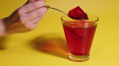 Dessert. Female hand takes a cherry jelly with a spoon.