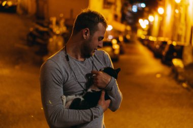 Kedi. Bir adam bahçe kedisini okşuyor. İtalya. Terracina..