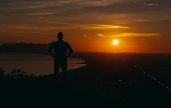 旅だ男が山の上に立って夕日を見る — ストック写真