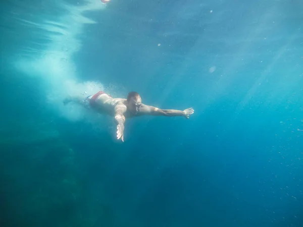 那家伙从悬崖下潜到海里 在水里游泳 — 图库照片