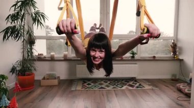 Uçan Yoga. Dairesinde hamakta yoga egzersizi yapan bir kadın..
