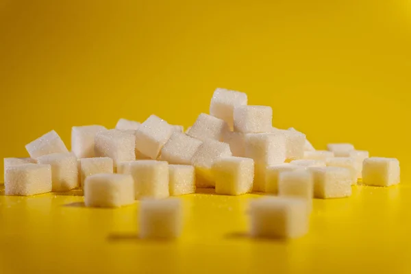 Sugar. Sugar cubes lie on a yellow background.