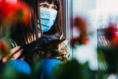 Virüs. Bir kadın, virüsten korunan gazlı bez maskeli bir kediyle oturuyor..