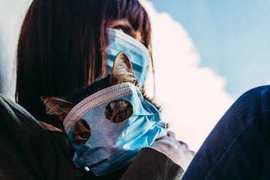 Virüs. Bir kadın, virüsten korunan gazlı bez maskeli bir kediyle oturuyor..