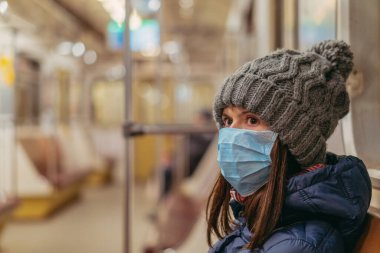 Tıbbi maske. Tıbbi maskeli bir kadın metro trenine biniyor. Ukrayna. Kiev.