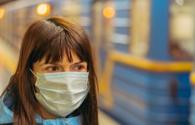 Tıbbi maske. Tıbbi maskeli bir kadın metroda tren bekliyor. Ukrayna. Kiev.