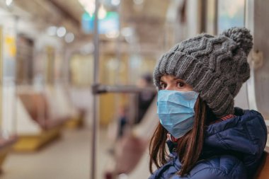 Tıbbi maske. Tıbbi maskeli bir kadın metro trenine biniyor. Ukrayna. Kiev.