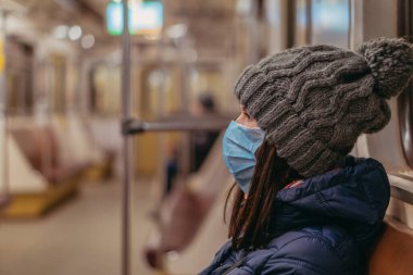 Tıbbi maske. Tıbbi maskeli bir kadın metro trenine biniyor. Ukrayna. Kiev.