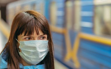 Tıbbi maske. Tıbbi maskeli bir kadın metroda tren bekliyor. Ukrayna. Kiev.