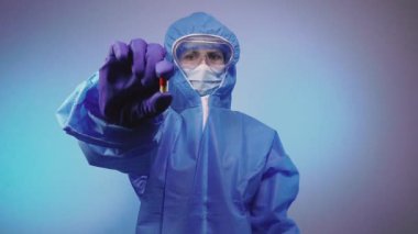 Virüs. Virüse karşı koruyucu giysi giyen bir doktor elinde bir tablet tutuyor..