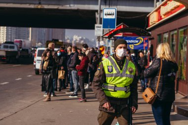 KYIV, UKRAINE - 19 Mart. 2020 yılı. COVID-19 virüsü yüzünden Kiev şehrinde karantina var. İnsanlar virüse karşı koruyucu maskelerle toplu taşıma duraklarında duruyorlar..
