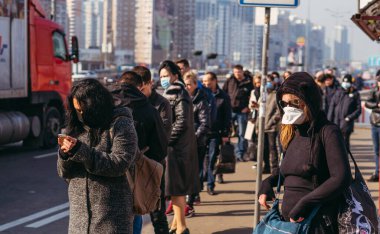 KYIV, UKRAINE - 19 Mart. 2020 yılı. COVID-19 virüsü yüzünden Kiev şehrinde karantina var. İnsanlar virüse karşı koruyucu maskelerle toplu taşıma duraklarında duruyorlar..