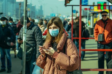 KYIV, UKRAINE - 19 Mart. 2020 yılı. COVID-19 virüsü yüzünden Kiev şehrinde karantina var. İnsanlar virüse karşı koruyucu maskelerle toplu taşıma duraklarında duruyorlar..