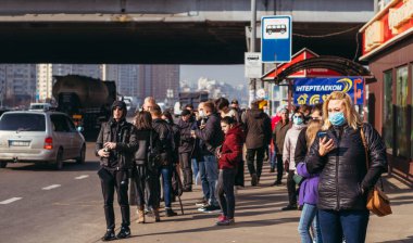 KYIV, UKRAINE - 19 Mart. 2020 yılı. COVID-19 virüsü yüzünden Kiev şehrinde karantina var. İnsanlar virüse karşı koruyucu maskelerle toplu taşıma duraklarında duruyorlar..