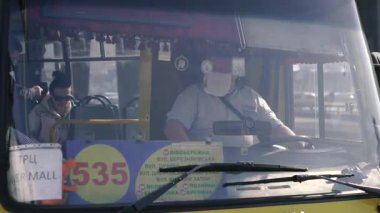 KYIV, UKRAINE - 19 Mart. 2020 yılı. COVID-19 virüsü yüzünden Kiev şehrinde karantina var. Minibüs sürücüsü virüse karşı koruyucu bir maske takıyor..
