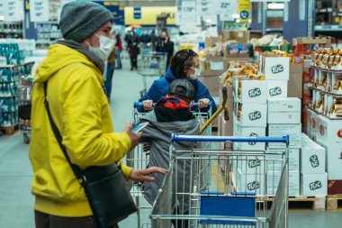 KYIV, UKRAINE - 27 Mart. 2020 yılı. COVID-19 virüsü yüzünden Kiev şehrinde karantina var. Tıp maskeli insanlar süpermarketten yiyecek satın alıyorlar..