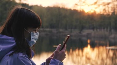 Virüs. Koruyucu maskeli bir kadın cep telefonuna bakıyor..