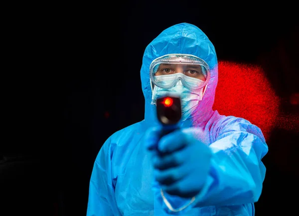 Non-contact thermometer. A man in a protective antivirus suit holds a beskotnny thermometer in his hands.