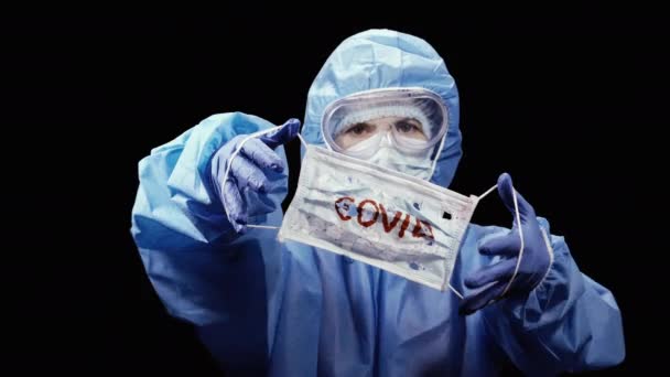 Coronavirus. Eine Frau im Antivirus-Schutzanzug hält eine medizinische Maske in den Händen.