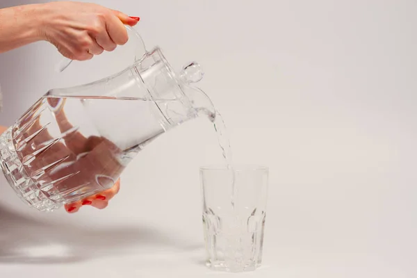 飲料水だ 女性の手は ガラスにデカンタから水を注ぐ — ストック写真