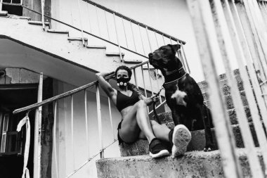 Kıyametten sonra. Hipoksik maskeli atletik kız tasmalı bir köpeği tutuyor..