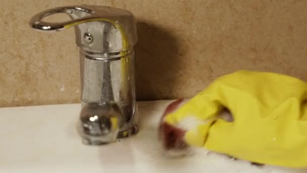 보호용 장갑을 욕실의 세면기와 세제를 사용하여 수도꼭지를 씻는다 — 비디오