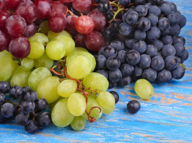 Farklı sınıflarda ve çiçek mavi ahşap arka plan üzerinde bir kutu içinde taze üzüm. 