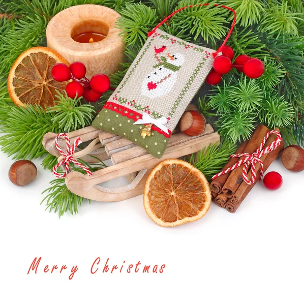 Decorative sledge, nuts, cinnamon and Christmas-tree decoration with a snowman on branches of a Christmas tree on a white background. A Christmas background with space for the text. — Φωτογραφία Αρχείου