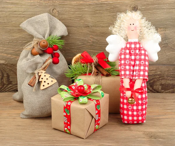Christmas gifts and a textile red Christmas angel on a gray wooden background. A Christmas background with space for the text. — Stock Photo, Image