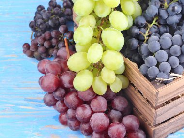 Bir ahşap kutu metin için yer bir mavi ahşap zemin üzerine farklı sınıflarda taze üzüm.