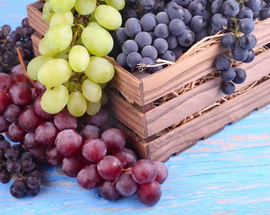  Bir ahşap kutu metin için yer bir mavi ahşap zemin üzerine farklı sınıflarda taze üzüm.