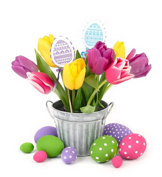 Bouquet of bright multi-colored tulips in a bucket and Easter eggs on a white background with space for the text. — Stock Photo, Image