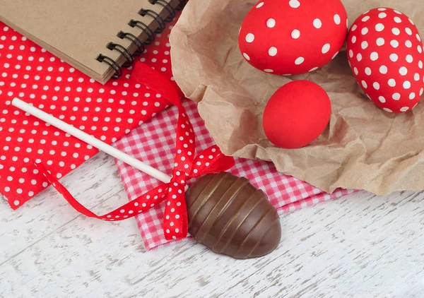 Huevo de chocolate en un palo y huevos rojos de Pascua sobre un fondo de madera. Un fondo de Pascua con espacio para el texto . —  Fotos de Stock