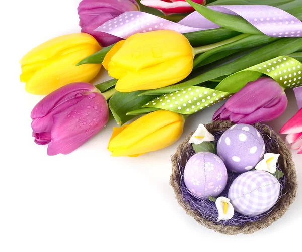 Tulipanes amarillos y violetas y huevos de Pascua sobre un fondo blanco. Un fondo de Pascua con espacio para el texto . Imagen de archivo