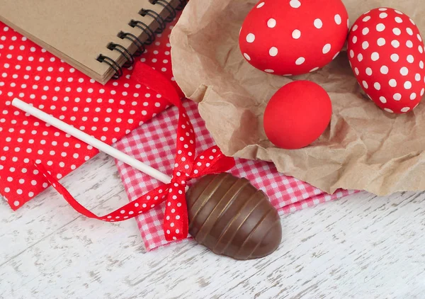 Čokoládové vajíčko na hůl a červené velikonoční vejce na dřevěné pozadí. Velikonoční pozadí s místem pro text. Stock Fotografie