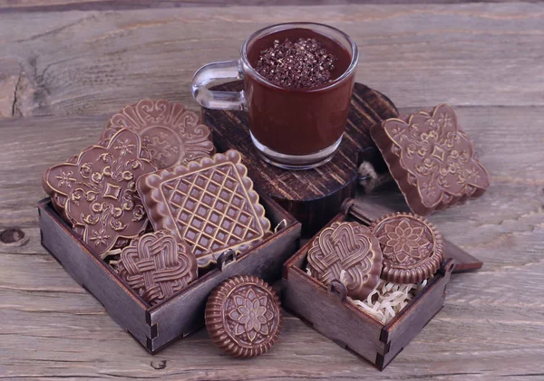 Fancy chocolate of handwork in boxes and a cup of hot chocolate  on a wooden background with space for the text. — Stock Photo, Image