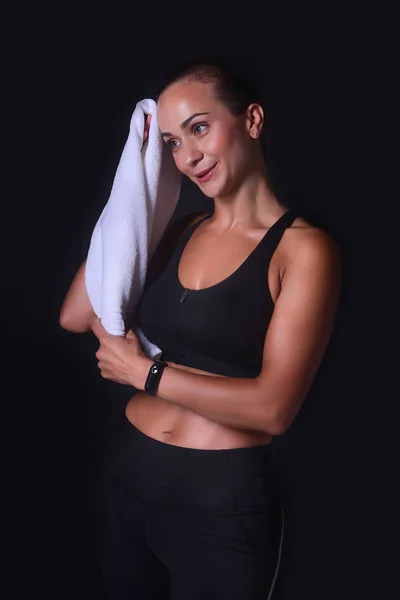 Hermosa chica atlética limpia el sudor con una toalla sobre un fondo negro después del entrenamiento — Foto de Stock